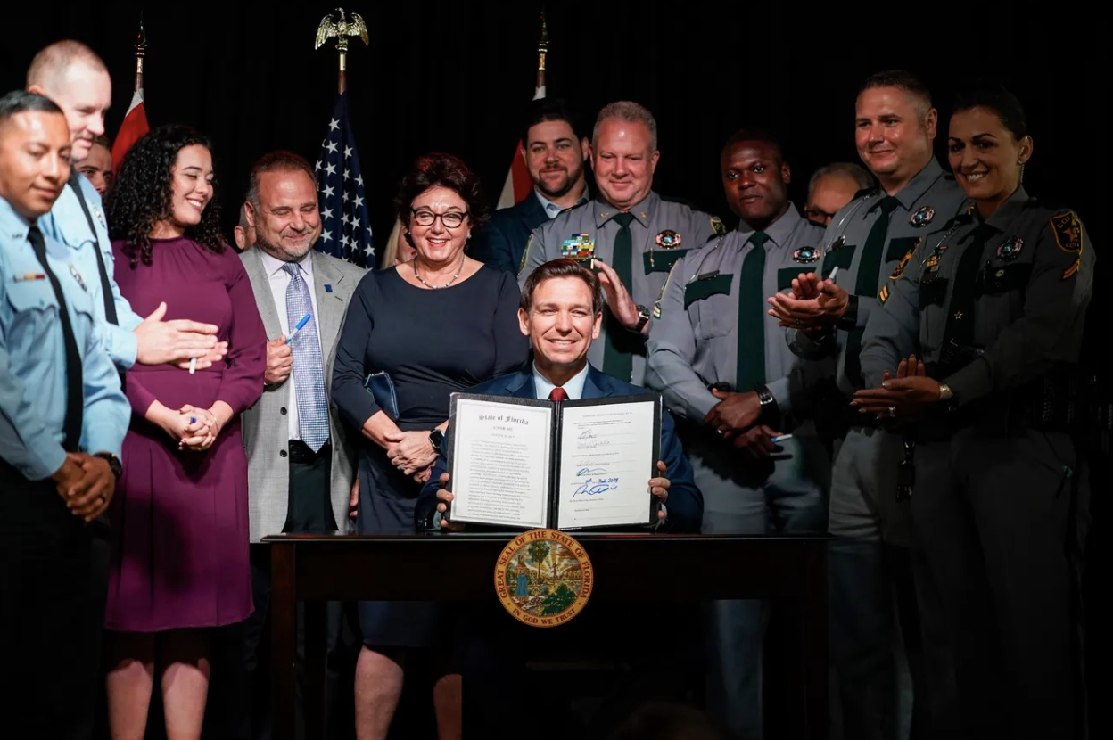Gov. Ron DeSantis holds up the signed Senate Bill 102